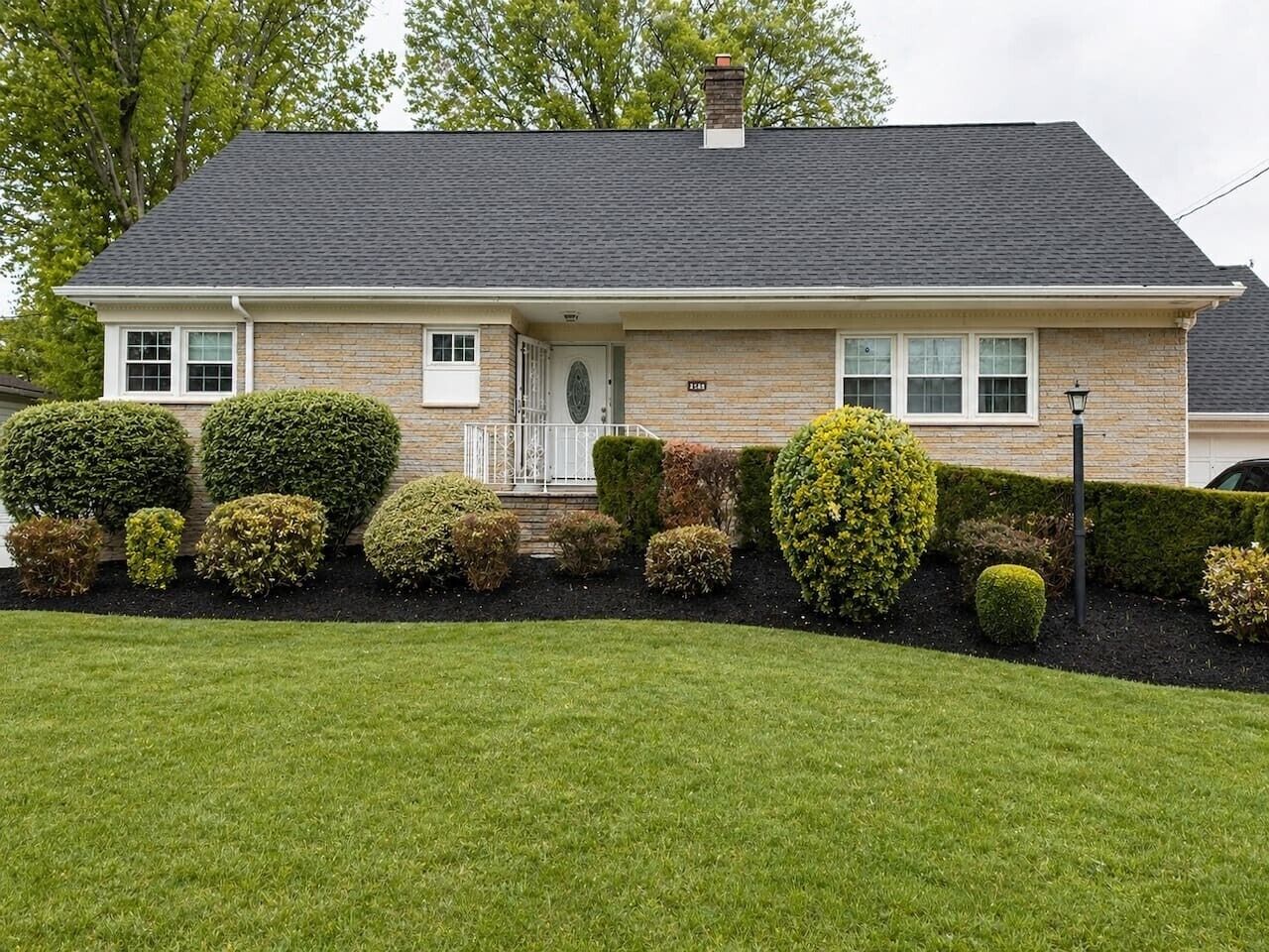 A two-story house with a front porch, a brick exterior, and a well-maintained lawn.