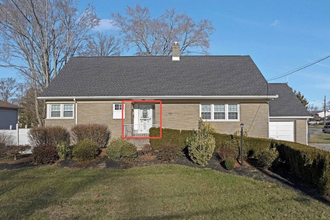 A single-story house with a front door, a garage, and a well-maintained lawn.