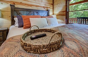 A wooden cabin bedroom with a bed, pillows, a remote control, and a woven basket.