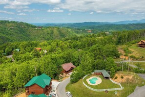 A lodge with multiple cabins, a swimming pool, and a scenic mountainous backdrop.