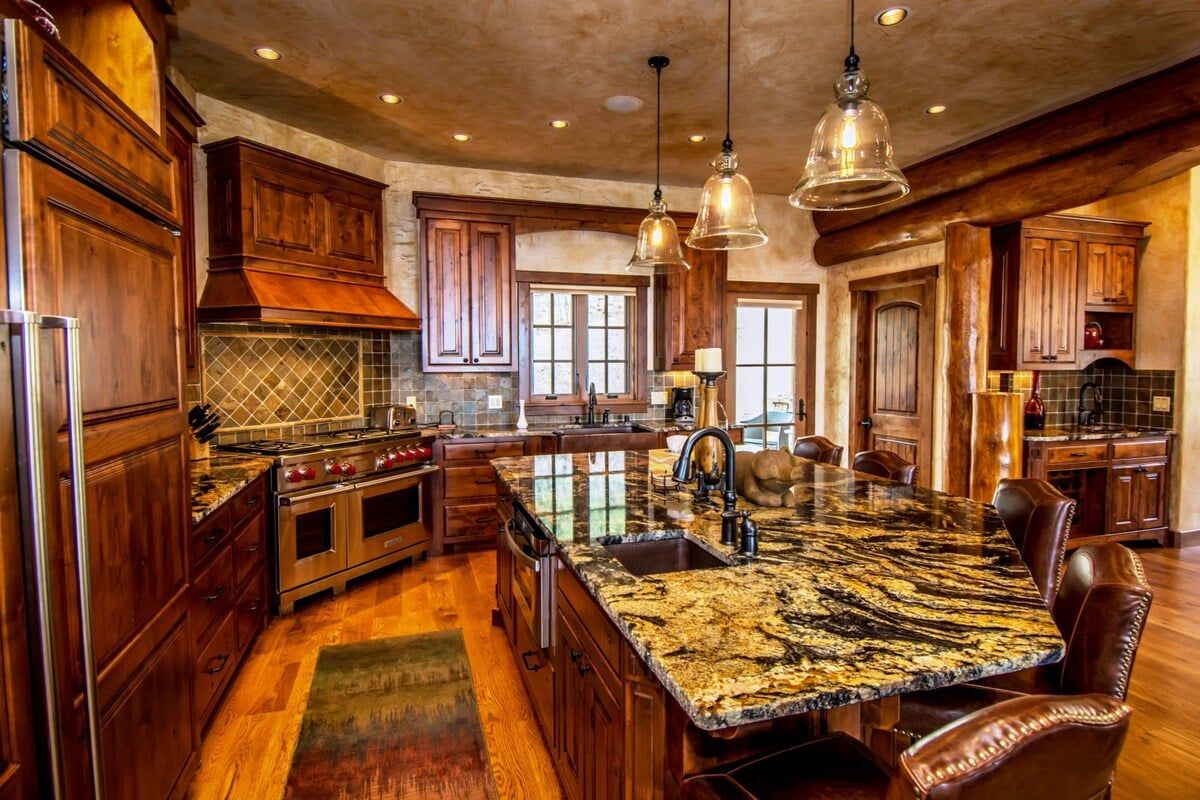 Una cocina amplia con una isla grande, armarios de madera e iluminación colgante.