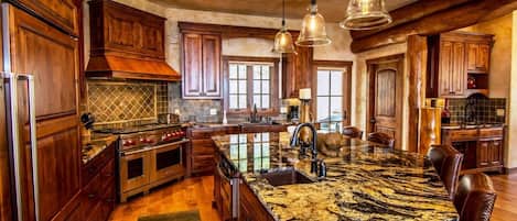 Una cocina amplia con una isla grande, armarios de madera e iluminación colgante.