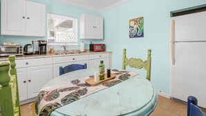 Una cocina con armarios blancos, un microondas y una mesa con mantel colorido.