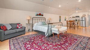 Une chambre comprenant un lit, un canapé, une chaise, une table à manger et un coin cuisine avec un réfrigérateur.