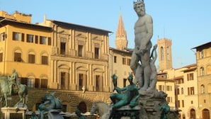 A historic square with classical statues and a prominent church tower.