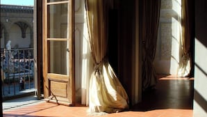 A room with a large window, a door, and a view of a public square with statues.