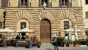A historic building with a central entrance, multiple windows, and a balcony with a statue.