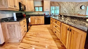 A kitchen with wooden cabinets, granite countertops, and a herringbone-patterned wall.