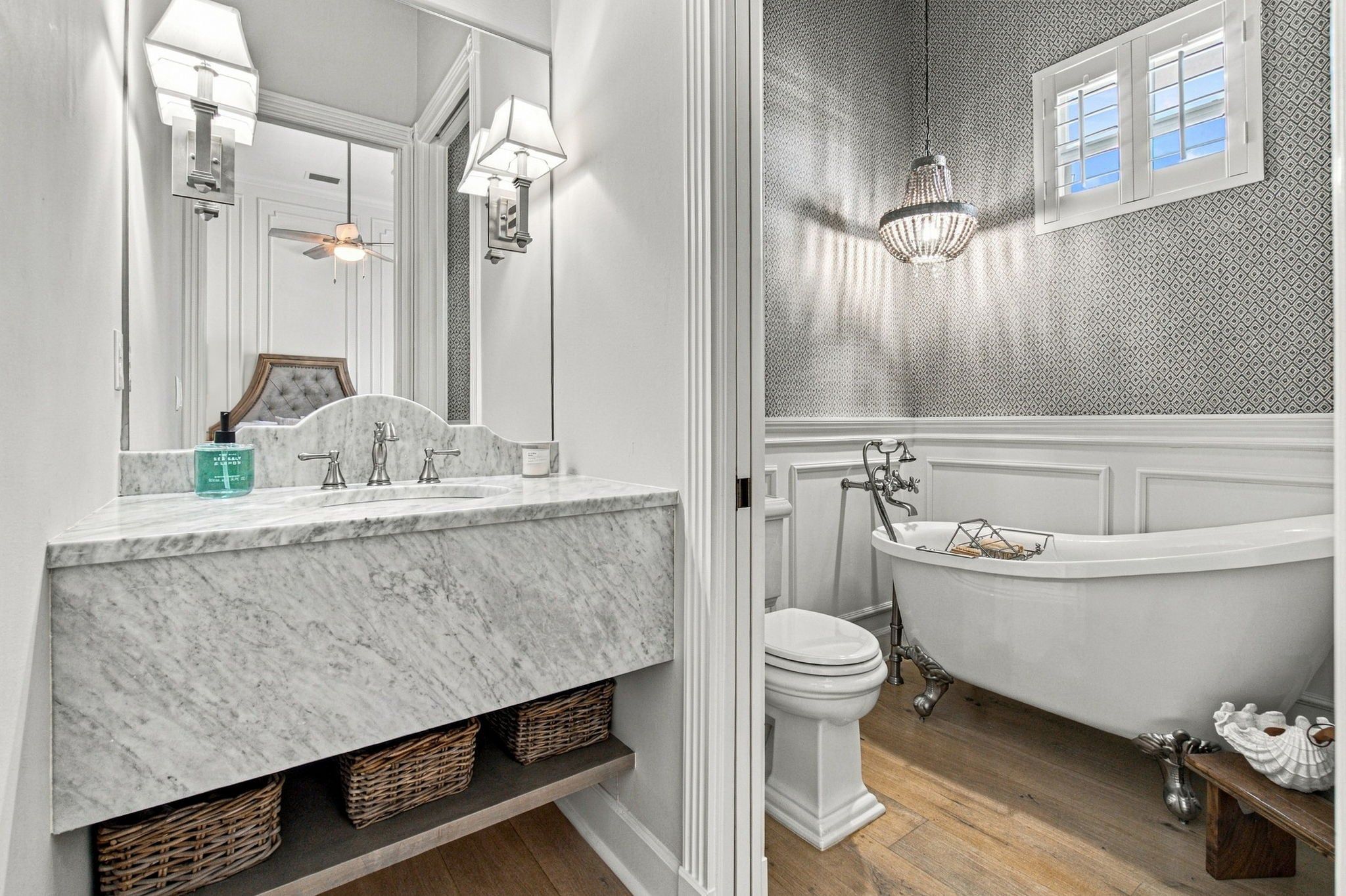 A bathroom with a marble sink, a freestanding bathtub, and a large mirror.