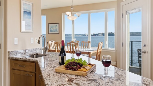 A kitchen with a marble countertop, a wine bottle, a glass of red wine, and a fruit platter. - Puget Sound waterfront · Rainier · fireplace (Tacoma)