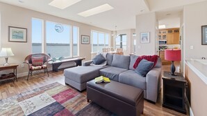 A living room with a sectional sofa, a small table, a chair, and a view of the water. - Puget Sound waterfront · Rainier · fireplace (Tacoma)
