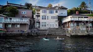 A waterfront property with a multi-level house, a dock, and a kayak in the water. - Puget Sound waterfront · Rainier · fireplace (Tacoma)