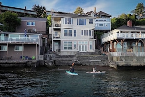 A waterfront property with a multi-level house, a dock, and a small boat. - Puget Sound waterfront · Rainier · fireplace (Tacoma)