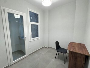 Una habitación con puerta de vidrio corredera, una mesita y una silla.