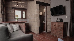 Una sala de estar con un sofá, un televisor montado en la pared, un mueble de madera y una pared de ladrillo.