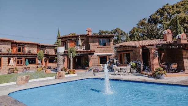 Una villa con piscina, mobiliario exterior y una fuente.