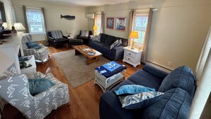 A living room with a sofa, armchairs, a coffee table, and a side table with a lamp. - A quintessential Cape Cod family home in Dennis Port (Dennis)