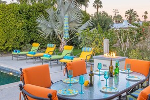 An outdoor patio with a pool, lounge chairs, and a fire feature. - Casa Del Solstice - Midcentury Pool & Spa Retreat (Palm Springs)