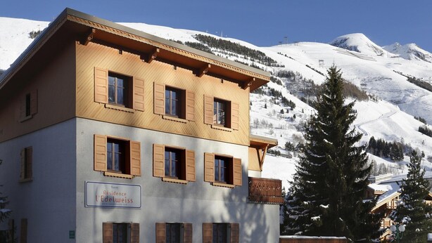 A two-story building with wooden shutters, a sign reading 'Residence l'Edelweiss,' and a snowy mountain backdrop. - Alpine Studio in Central Setting (Les Deux Alpes)