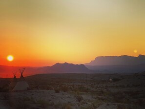 Un paysage désertique avec des montagnes en arrière-plan et un coucher de soleil.