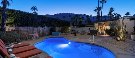 Un jardin avec une piscine, des chaises longues et une terrasse en bois.