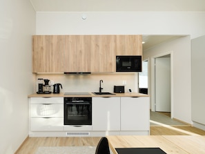 Eine moderne Küche mit Holzschränken, einer eingebauten Mikrowelle, einer Kaffeemaschine und einem Geschirrspüler.