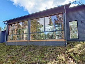 Ein modernes Gebäude mit großen Fenstern, einem geneigten Dach und einer Holzterrasse.