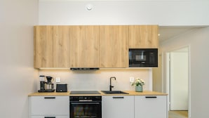 Eine moderne Küche mit Holzausstattung, einer Bosch-Mikrowelle, einer Kaffeemaschine, einem Toaster und einem Geschirrspüler.
