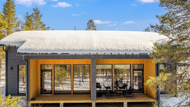 Eine moderne Holzhütte mit einer Holzterrasse und großen Fenstern.