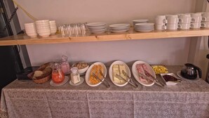 Un buffet est installé sur une table, avec des assiettes, des bols et des couverts à disposition.