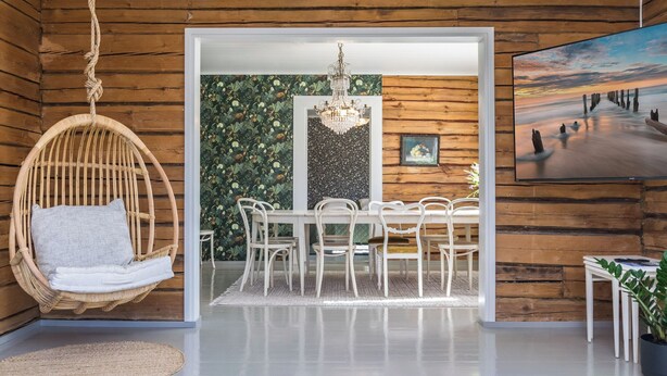 A room with a hanging chair, a dining table with chairs, a chandelier, and a large painting on the wall. - Virtaan tainio by Interhome (Sysmä)