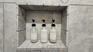 Three bottles of toiletries in a stone-walled alcove.