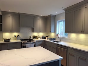 Una cocina moderna con gabinetes grises, encimera de mármol y ventana que proporciona luz natural.