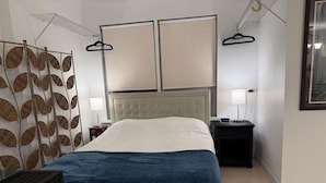 Ein Hotelzimmer mit Bett, Nachttischen, einer Pendelleuchte, einem an der Wand montierten Fernseher und einer Dekoration.
