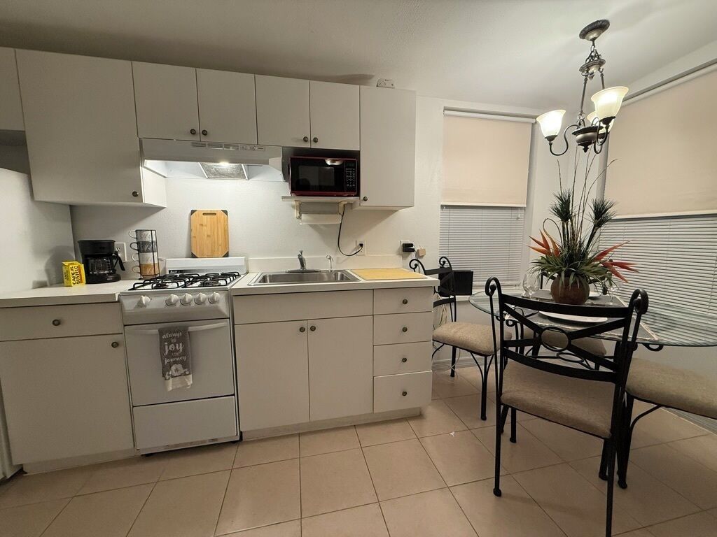 A compact kitchen with a gas stove, microwave, and a small dining area with a table and chairs.