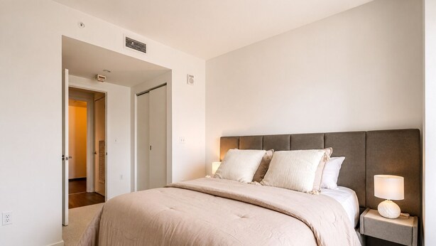 Une chambre à coucher avec un lit, des lampes de chevet et une porte donnant sur une autre pièce.