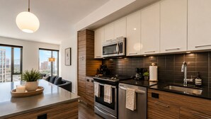 Une cuisine moderne dotée d’un îlot central, d’appareils électroménagers en acier inoxydable et offrant une vue sur la ville.