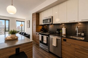 Eine moderne Küche mit Kochinsel, Edelstahlgeräten und Blick auf die Stadt.