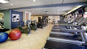 Ein Fitnessraum mit Laufbändern, Crosstrainern und Gymbällen.