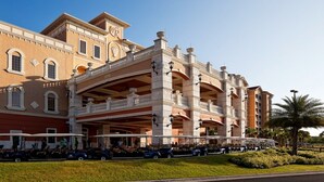 Ein mehrstöckiges Hotel mit einem prunkvollen Eingang, einem überdachten Außenbereich und einem Parkplatz mit Golftrolleys.