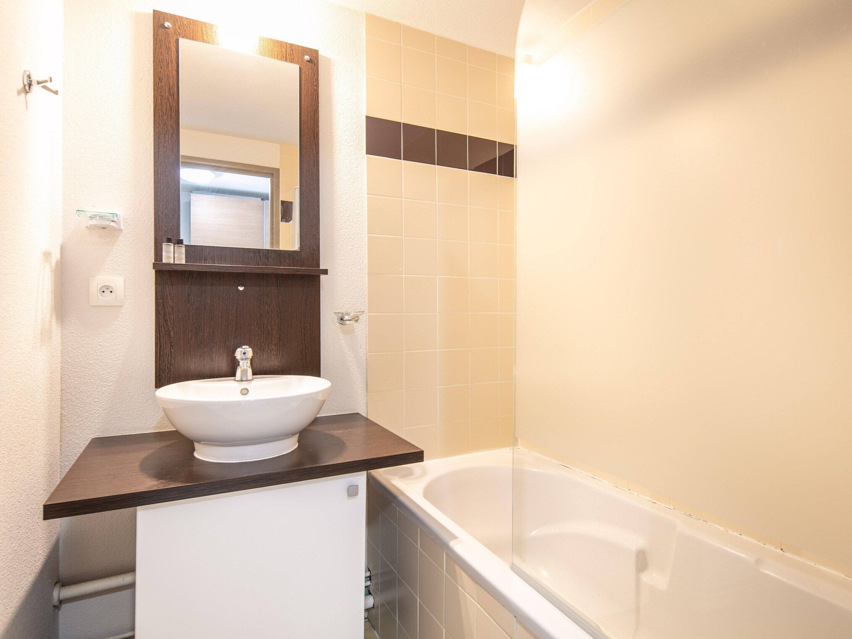 A bathroom with a white sink, a mirror, and a bathtub.