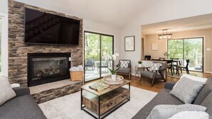 Una sala de estar con chimenea de piedra, un televisor de pantalla plana y un comedor con mesa y sillas.