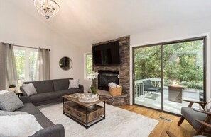 A living room with a fireplace, a sofa, a coffee table, and a view of the outdoors.