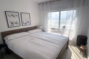 A bedroom with a large bed, a view of the ocean, and two framed floral artworks on the wall. - Beachfront apartment with sea views. (Estepona)
