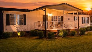 A single-story mobile home with a covered porch and a small front yard.