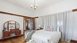 A bedroom with a bed, a dresser, a mirror, a chandelier, and a view of another room. - Spacious Stay in New Norfolk (New Norfolk)