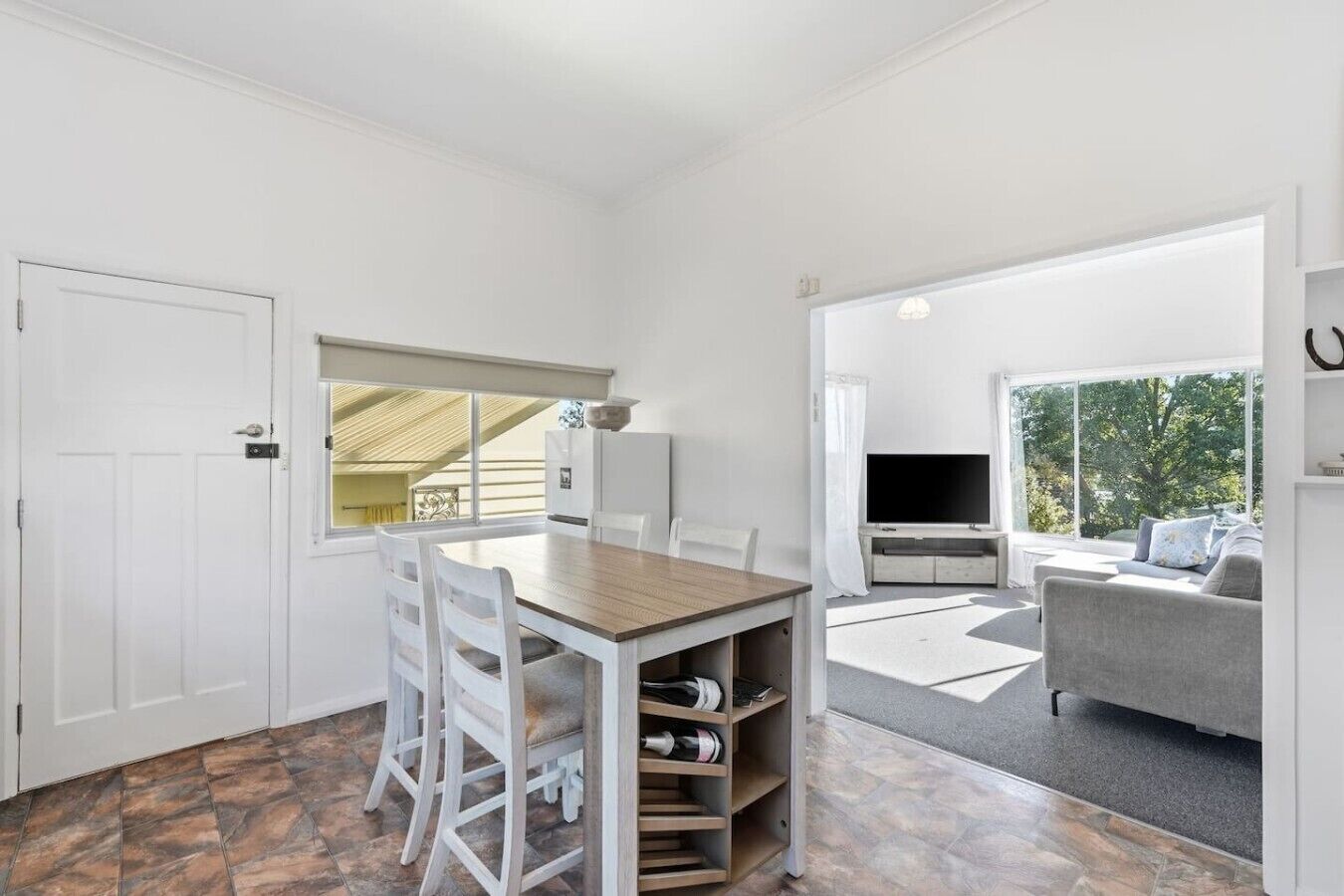 A room with a dining table, chairs, a TV, and a sofa.