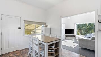 A room with a dining table, chairs, a TV, and a sofa.
