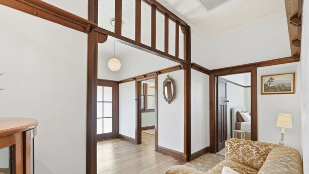 A spacious room with a high ceiling, wooden beams, a large window, and a sofa with patterned cushions. - Spacious Stay in New Norfolk (New Norfolk)