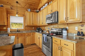 A kitchen with wooden cabinets, a stainless steel oven, a microwave, and a granite countertop. - Honeymoon Ridge- Luxury Mountaintop Cabin (Bryson City)